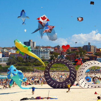 Festival of the Winds — giant colourful kites fill the sky above Bondi Beach with the city skyline behind